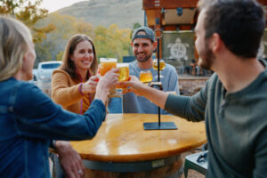 New Terrain Brewing Company four people cheers with beer outdoors in the beer garden on a fall day