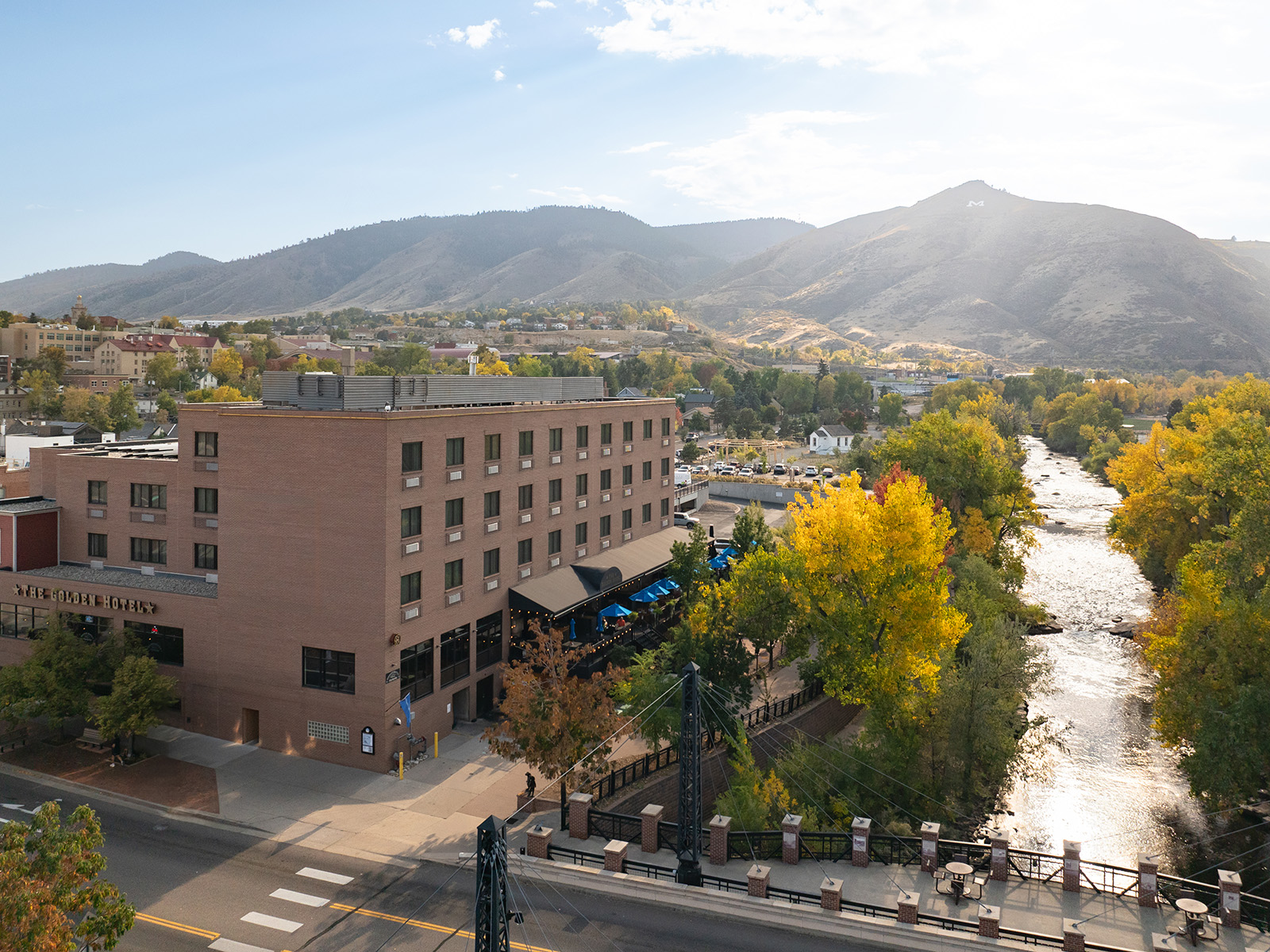 Aerial view of the Golden Hotel along Clear Creek, surrounded by fall foliage and the foothills.