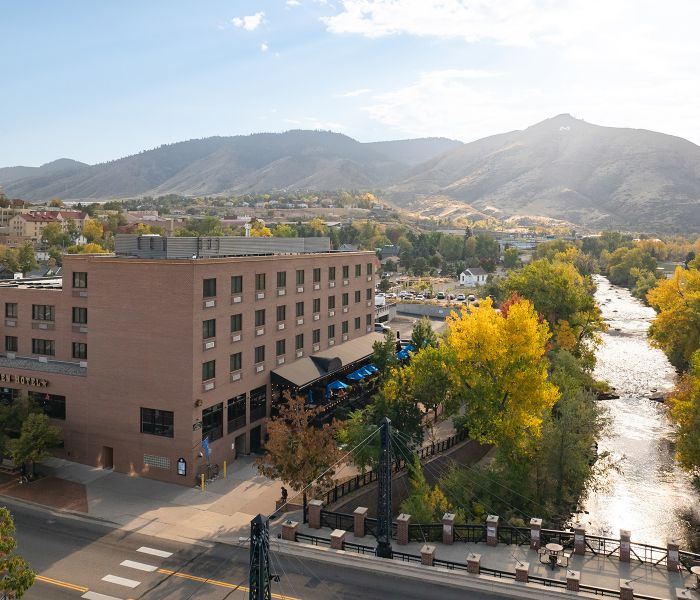 Aerial view of the Golden Hotel along Clear Creek, surrounded by fall foliage and the foothills.