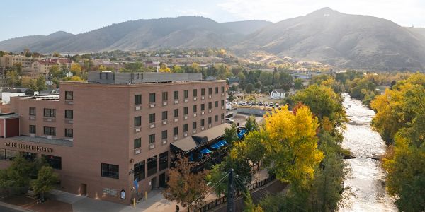 Aerial view of the Golden Hotel along Clear Creek, surrounded by fall foliage and the foothills.