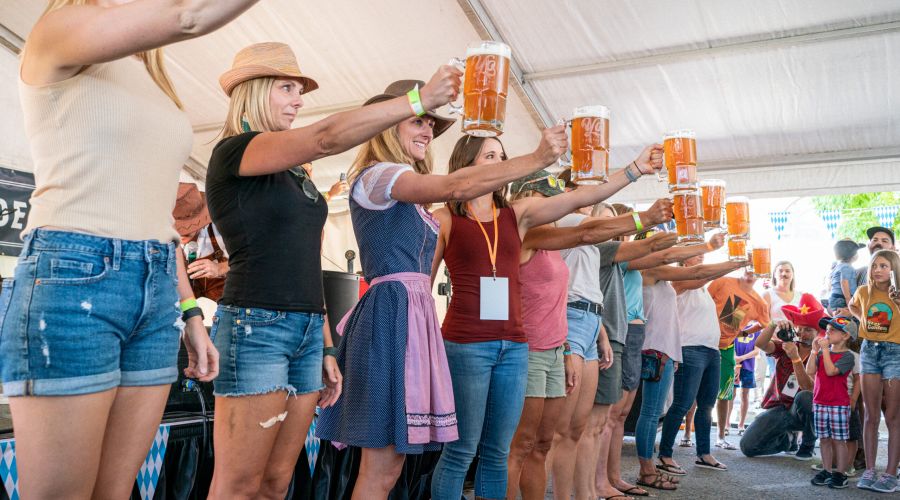 A group holding full beer steins in an endurance competition at Oktoberfest 2022