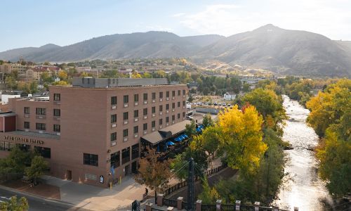 Aerial view of the Golden Hotel along Clear Creek, surrounded by fall foliage and the foothills.
