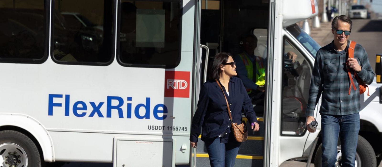 Two people walking off and away from an on-demand, curb-to-curb RTD FlexRide bus.